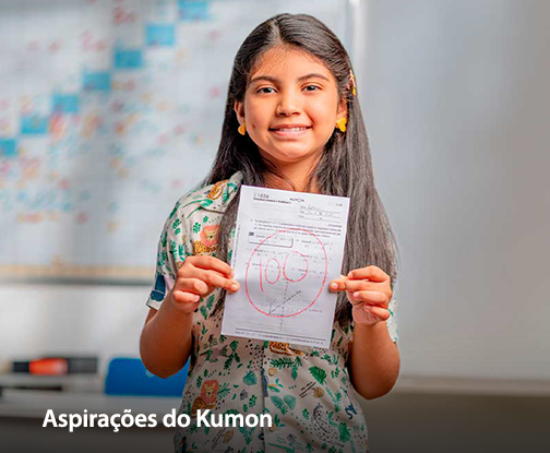 Aluna feliz segurando o material de papel do Kumon monstrando a sua nota cem que tirou